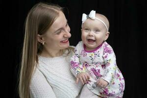 Mom holds a little happy daughter in her arms. Motherhood. photo