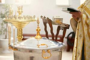 Baptism rite. Font for Orthodox baptism and the priest reads a prayer. photo