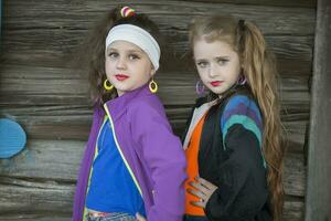 Little girls in bright clothes with makeup on their faces on a wooden background. A child in the style of the nineties. photo