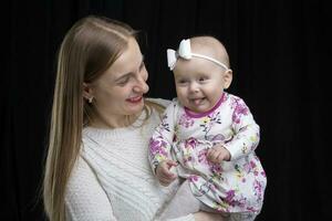 Mom holds a little happy daughter in her arms. Motherhood. photo