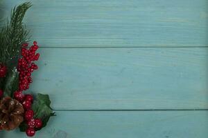 On a turquoise wood background, a decoration of a spruce branch and cones. Christmas background. photo