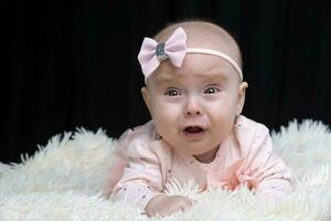 The beautiful baby is crying and capricious. Baby at four months old. A funny child. photo