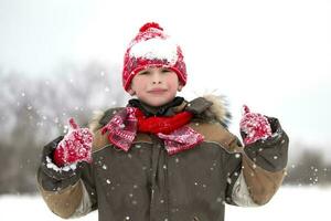 Children in winter. The happy boy plays in the snow. photo