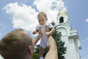 julio 20, 2020, bielorrusia, el ciudad de gomil, un Iglesia en el ciudad. ortodoxo bautismo de un niño. el padre elevado el niño en contra el antecedentes de el cielo y el iglesia. foto