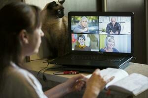 Back view of a business woman talking with her colleagues about an outline in a video conference. Business team using laptop for online meeting in video call. photo