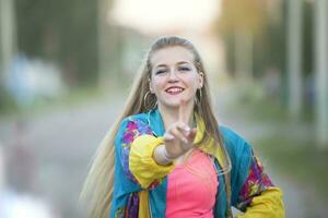 hermosa rubia niña vestido en el estilo de el noventa bailando en el calle. foto