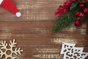 On a wooden background, a toy wood tree, a snowflake and a decoration of a fir branch and cones. Christmas background. photo