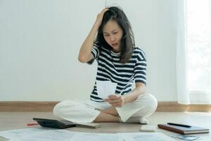 Stressed and headache asian woman with large bills or invoices no money to pay to expenses and credit card debt. shortage, Financial problems, mortgage, loan, bankruptcy, bankrupt, poor, empty wallet photo