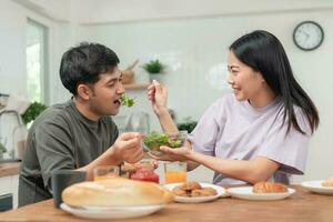 Asian couples are enjoying new home and eating breakfast together. husband and wife after marriage. Happiness and smiles and laughter in warm family. cuddling, warm hugs, Happy family and happy day. photo