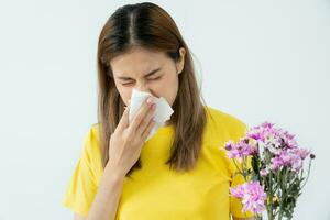 Pollen Allergies, asian young woman sneezing in a handkerchief or blowing in a wipe, allergic to wild spring flowers or blossoms during spring. allergic reaction, respiratory system problems photo