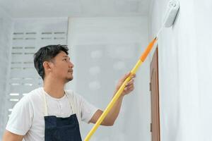 pintor hombre, cepillo en mano para productos a restaurar y pintar el muro, interior el edificio sitio de un casa, pared durante cuadro, renovación, cuadro, contratista, arquitecto, construcción trabajador foto