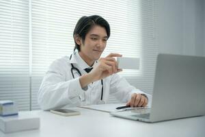 telemedicina. el médico explica el medicamento al paciente por videoconferencia. el médico asiático está tratando a los pacientes a través de las telecomunicaciones mientras describe la enfermedad. tecnología para la salud. foto