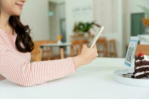 Woman use smartphone to scan QR code for order menu in cafe restaurant with a digital delivery. Choose menu and order accumulate discount. E wallet, technology, pay online, credit card, bank app. photo