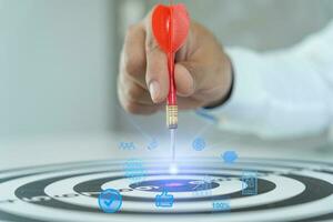Businessman set goals for work. Hand holding a dart aiming at the target center business. goal, aiming marketing target metaphor, Succeed dart board, defines objectives, success investment ideas. photo