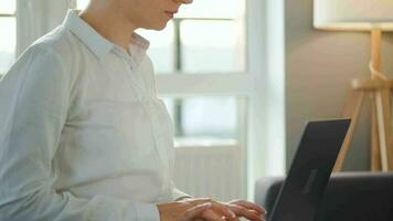 femme est séance sur le canapé et travail sur une portable. concept de éloigné travail video