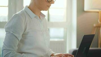 donna è seduta su il divano e Lavorando su un' il computer portatile. concetto di a distanza opera video