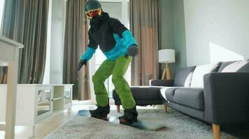 Fun video. Man dressed as a snowboarder rides a snowboard on a carpet in a cozy room. Waiting for a snowy winter video