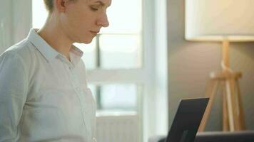 vrouw is zittend Aan de bankstel en werken Aan een laptop. concept van afgelegen werk video