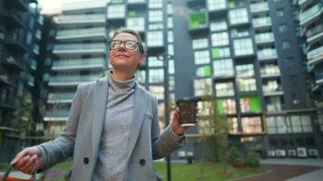 vrouw wandelen Aan een bedrijf wijk houdt meenemen koffie boodschappen doen Tassen en toepassingen smartphone video