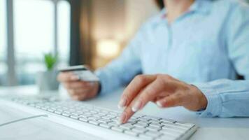 mujer mecanografía crédito tarjeta número en computadora teclado. ella haciendo en línea compra. en línea pago servicio. video