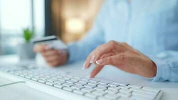 mujer mecanografía crédito tarjeta número en computadora teclado. ella haciendo en línea compra. en línea pago servicio. video