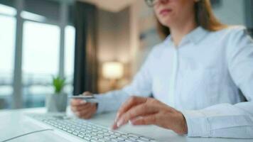 mujer mecanografía crédito tarjeta número en computadora teclado. ella haciendo en línea compra. en línea pago servicio. video