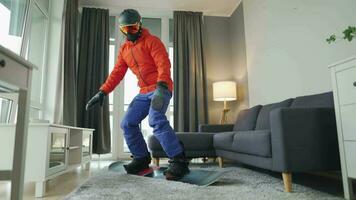 Fun video. Man dressed as a snowboarder rides a snowboard on a carpet in a cozy room. Waiting for a snowy winter video