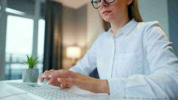 mujer con lentes mecanografía en un computadora teclado. concepto de remoto trabajo video