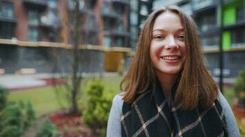 Portrait of a gorgeous dark haired woman smiling charmingly while standing against the background of modern buildings video