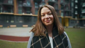 Portrait of a gorgeous dark haired woman smiling charmingly while standing against the background of modern buildings video