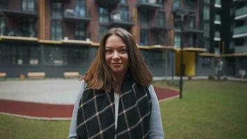 portret van een prachtig donker haren vrouw glimlachen charmant terwijl staand tegen de achtergrond van modern gebouwen video