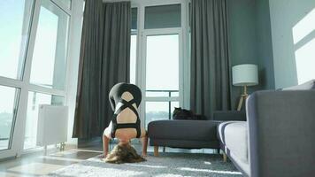 Young caucasian woman in black jumpsuit doing yoga at home to develop flexibility and balance. Slow motion video