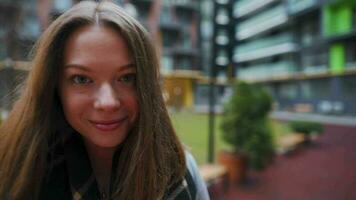 portret van een prachtig donker haren vrouw glimlachen charmant terwijl staand tegen de achtergrond van modern gebouwen video