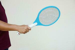 Closeup hand holds mosquito electric swatter racket. Concept, electric device to kill mosquitoes, insects, bugs by swatting to flying insects that can cause disease or annoyed feeling. photo