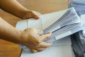 Closeup hands hold stack of used paper to recycle or combine to use next time to print out both sides of paper. Concept, eco friendly activity for environment, reuse paper. photo