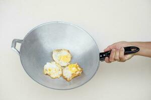 Closeup hand hold pan of fried eggs. Concept, love cooking. Fast and easy eggs menu. Food ingredient. Recipe. Kitchen lifestyle. Asian food, High protein nutrition. photo