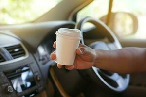 Closeup hand hold paper cup of coffee to drink in car. Concept, baverge for refreshing or helping to awake from asleep during driving that can cause car accident. photo