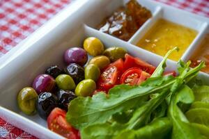 Close-up of pickled olives and herbs and spices on a wooden plate. photo