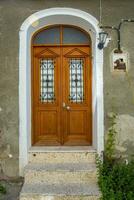 A wooden double door, with dark brown windows with a stone wall. photo