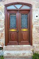 A wooden double door, with dark brown windows with a stone wall. photo