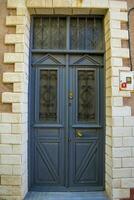 A wooden double door, with dark brown windows with a stone wall. photo
