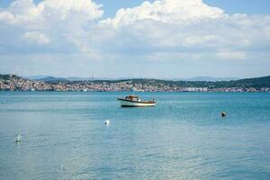 An old and small fishing boat in the background of a Turkish town on a summer and sunny day. photo