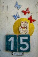 A sign with the number 15, butterflies, and a cat. photo