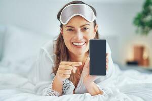 Brunette woman on bed with phone photo