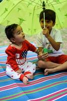 Two happy boys in society park, happy Asian brothers who are smiling happily together. Brothers play outdoors in summer, best friends. Toddler baby boy playing with his happy brother in the garden photo