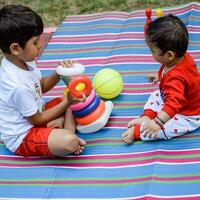 dos contento Niños en sociedad parque, contento asiático hermanos quien son sonriente felizmente juntos. hermanos jugar al aire libre en verano, mejor amigos. niñito bebé chico jugando con su contento hermano en el jardín foto