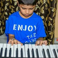 Asian boy playing the synthesizer or piano. Cute little kid learning how to play piano. Child's hands on the keyboard indoor. photo