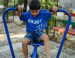 Asian boy doing routine exercise in society park during the morning time. Cute little kid exercise and gym to keep himself fit for life. Child's exercise outdoor shoot photo