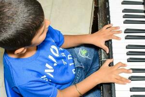 Asian boy playing the synthesizer or piano. Cute little kid learning how to play piano. Child's hands on the keyboard indoor. photo