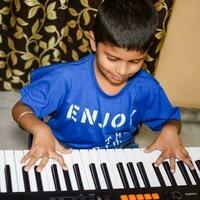 asiático chico jugando el sintetizador o piano. linda pequeño niño aprendizaje cómo a jugar piano. niño manos en el teclado interior. foto